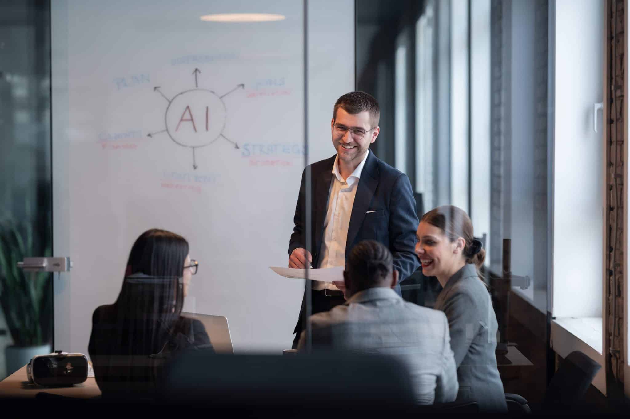 Faculty and professionals collaborate in a glass-walled classroom at Generations College, discussing an AI strategy illustrated on a whiteboard.